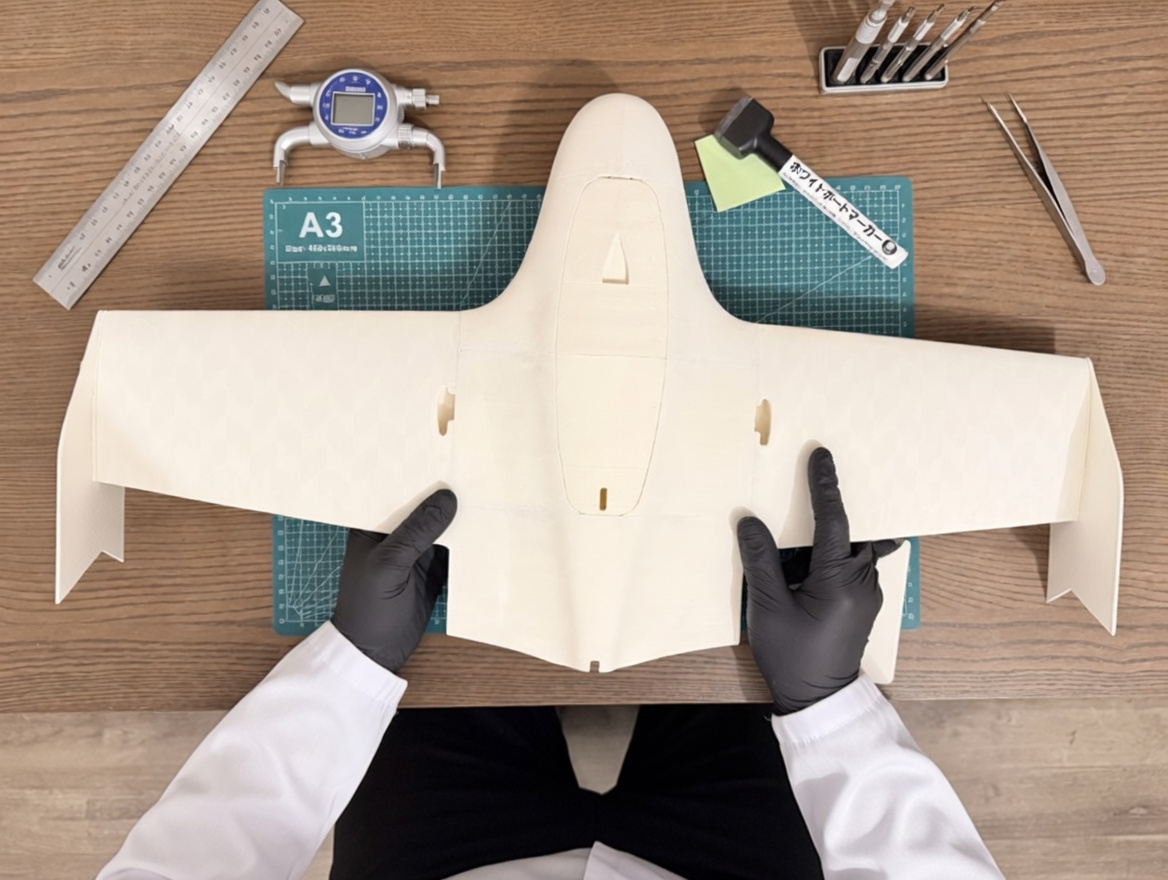 Person working on aircraft model with precision tools on desk